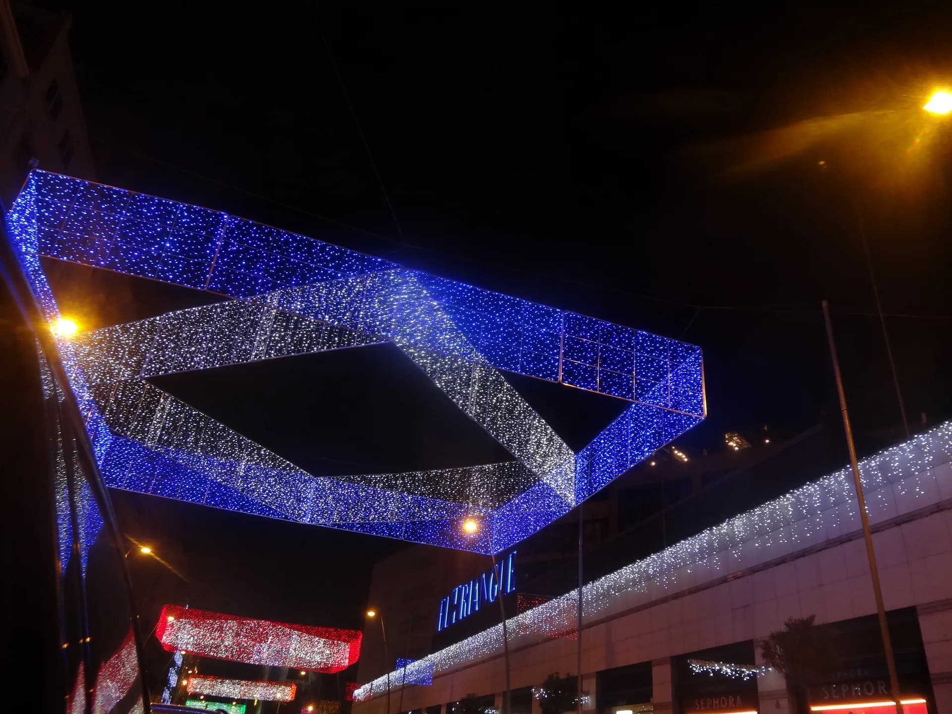Llums de Nadal blaves i blanques sobre un carrer comercial de Barcelona, de nit