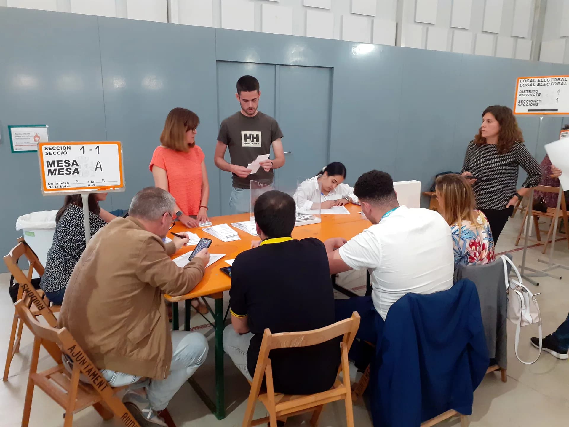 Un grup de persones comptant vots al voltant d'una taula, amb el cartell de la mesa electoral