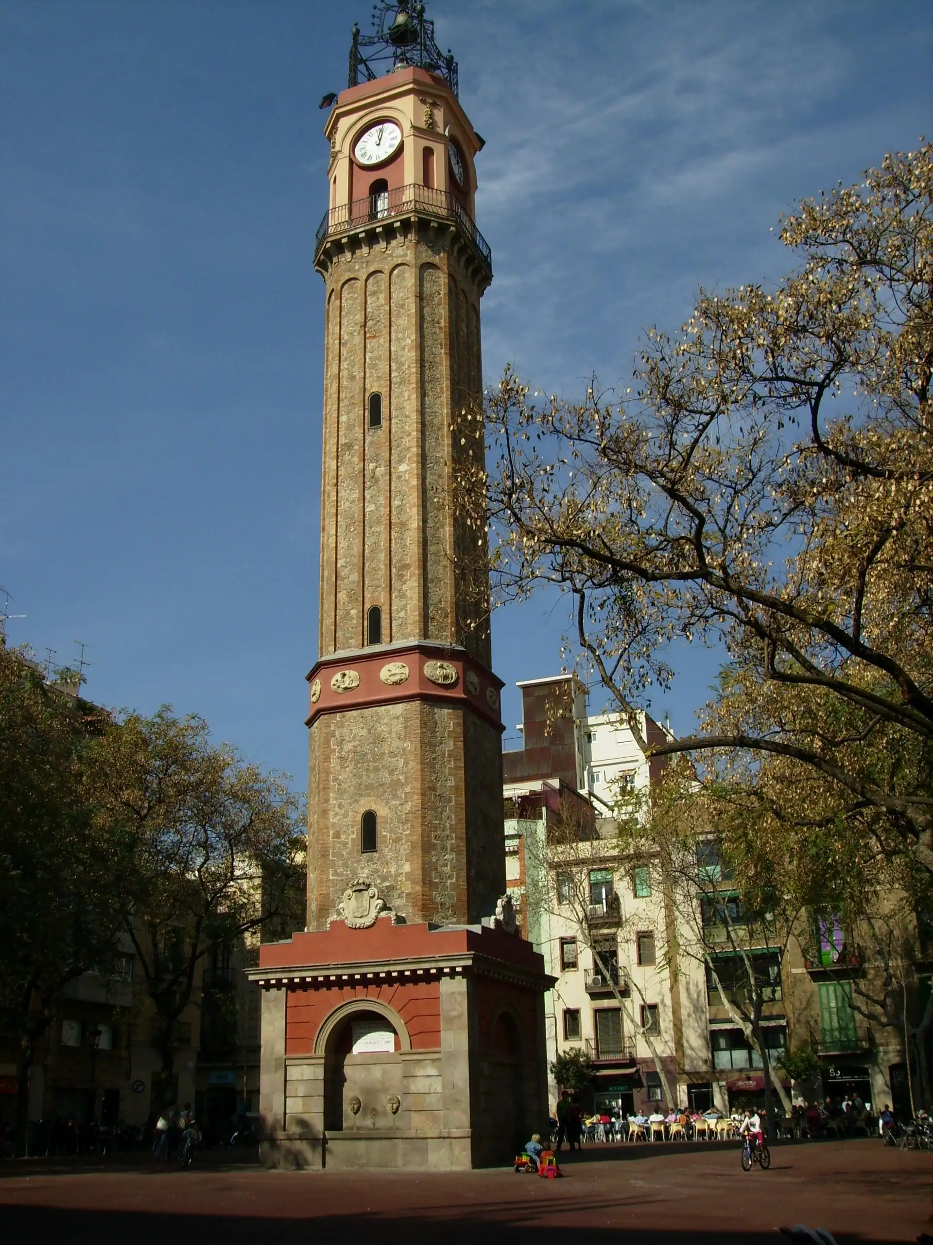 La torre del rellotge de la plaça de la Vila de Gràcia, a Barcelona, amb arbres de tardor