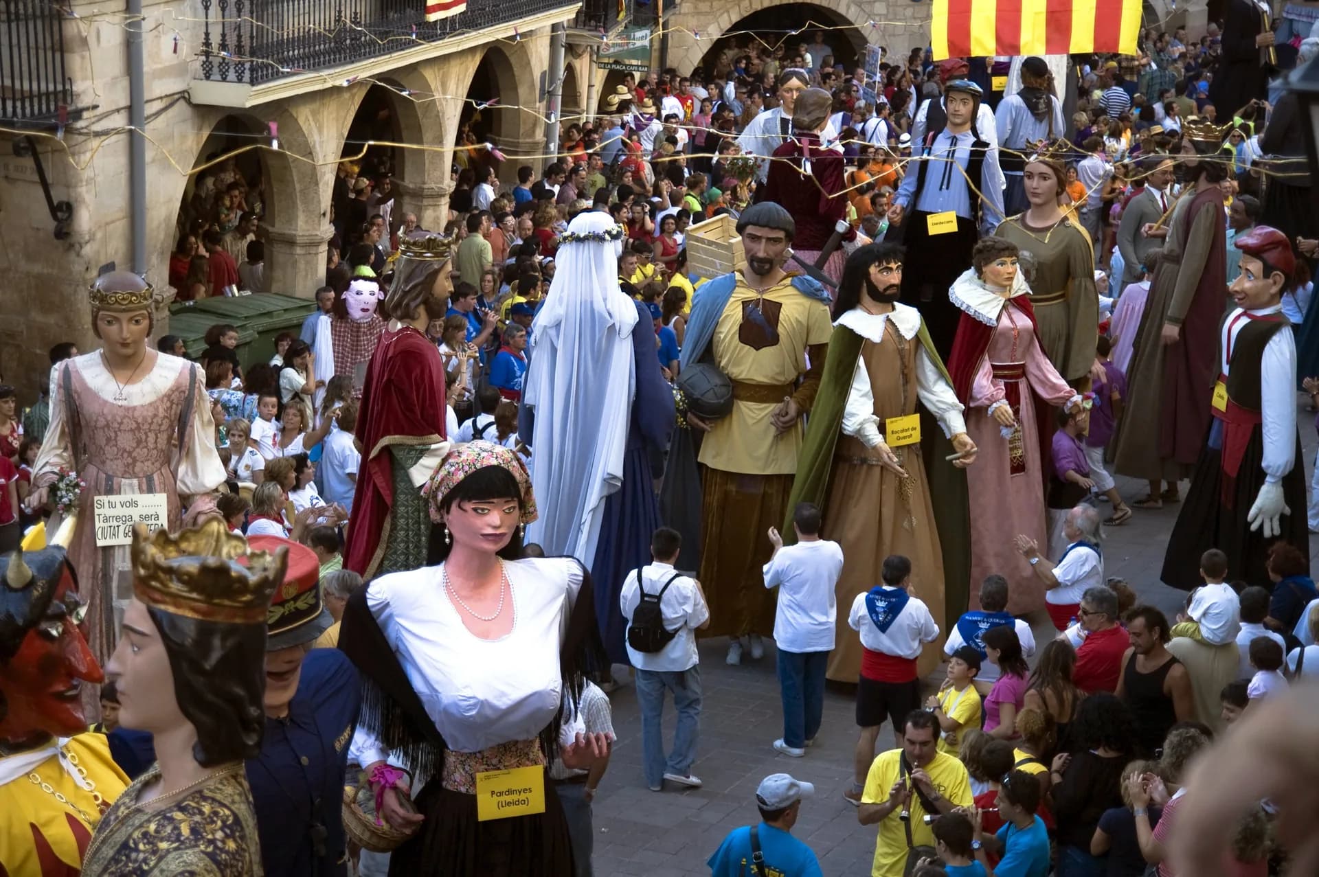 Giant figures parading through a crowded street during a festa major in Catalonia