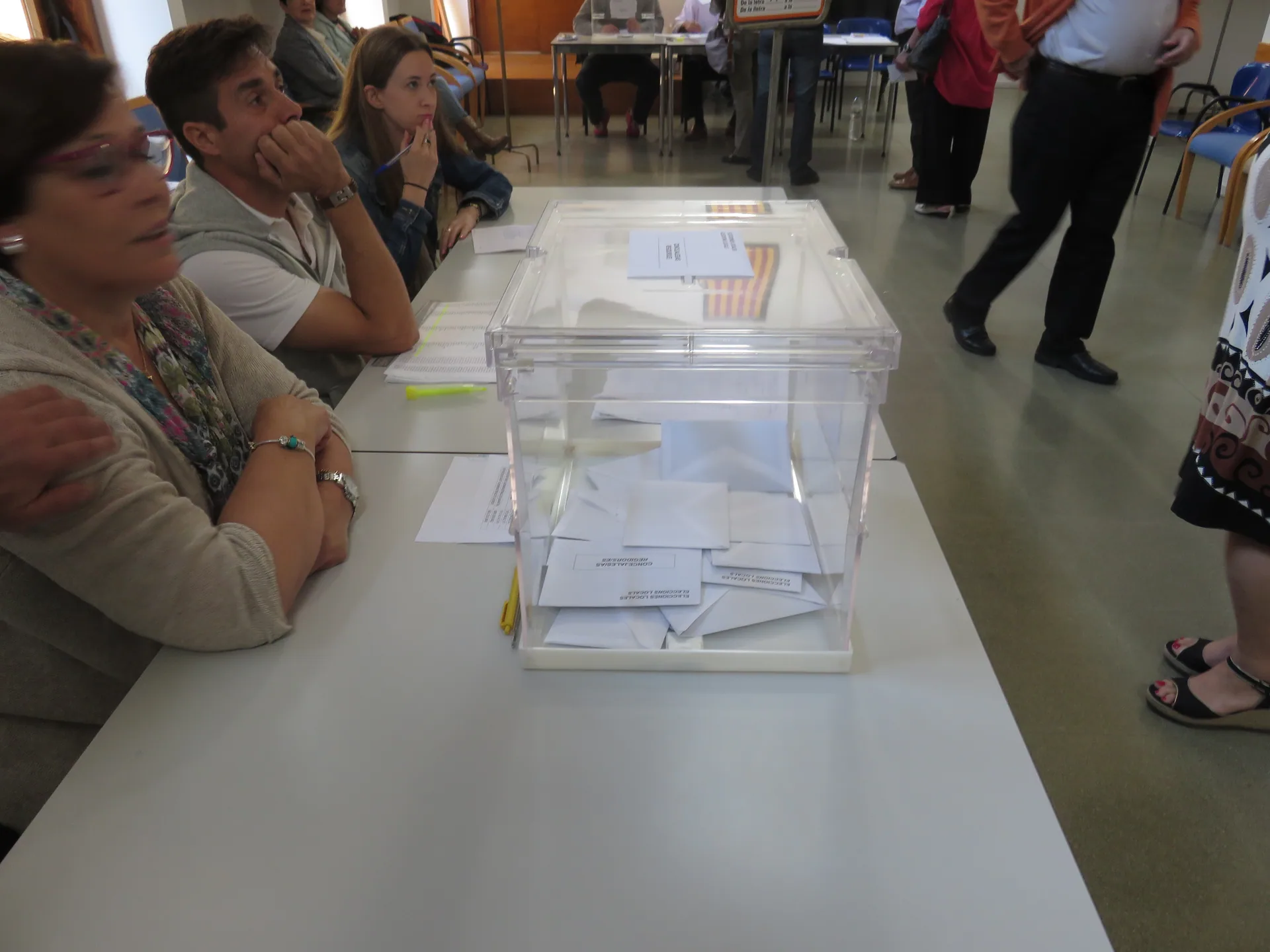 Miembros de una mesa electoral sentados detrás de la urna durante la votación