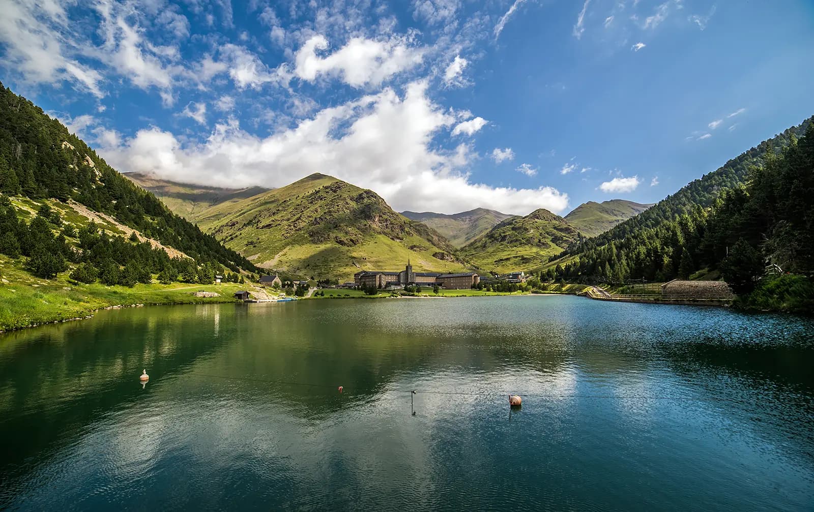 The Núria lake with the sanctuary and hotel behind it, between green mountains
