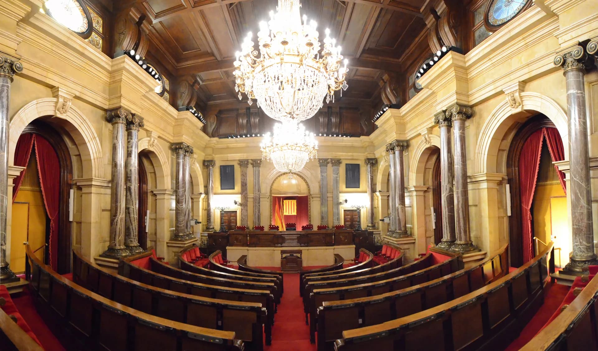 La Sala de Plens del Parlament de Catalunya, amb els escons vermells i les làmpades