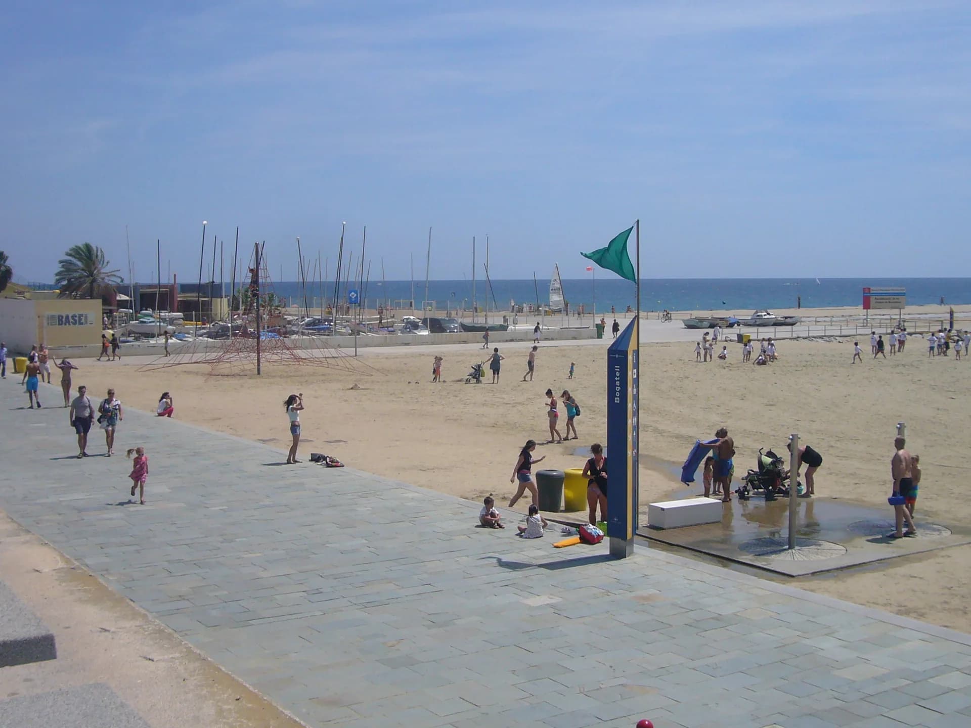 La playa del Bogatell con la bandera verde, las duchas y el tótem de información